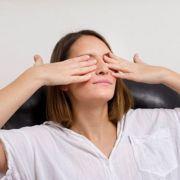 Femme, yeux fermés, mains sur visage, chaise noire, chemise blanche