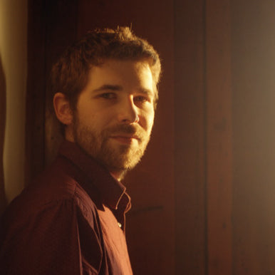 Homme barbu, chemise rouge, lumière douce, sourire, mur en bois