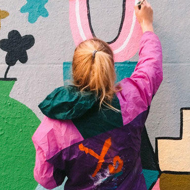 Enfant dessine sur mur, sac à dos arc-en-ciel, fleurs, escalier, mur coloré